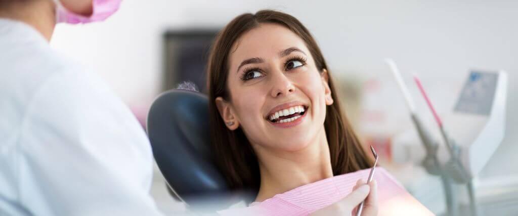Dental Crowns vs. Veneers: Understanding the Differences in Cosmetic Dentistry Woman in dental chair smiling
